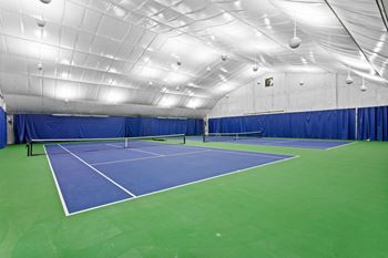 A tennis court in a gym with a blue and green court